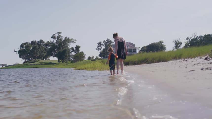 A mother walks with her son on the beach