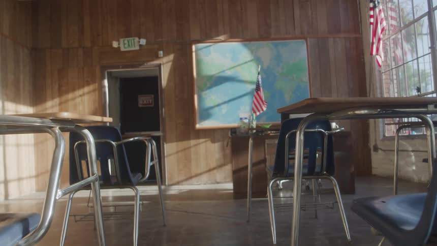 Empty classroom with blue chairs and desks united states flags and a world map in the background