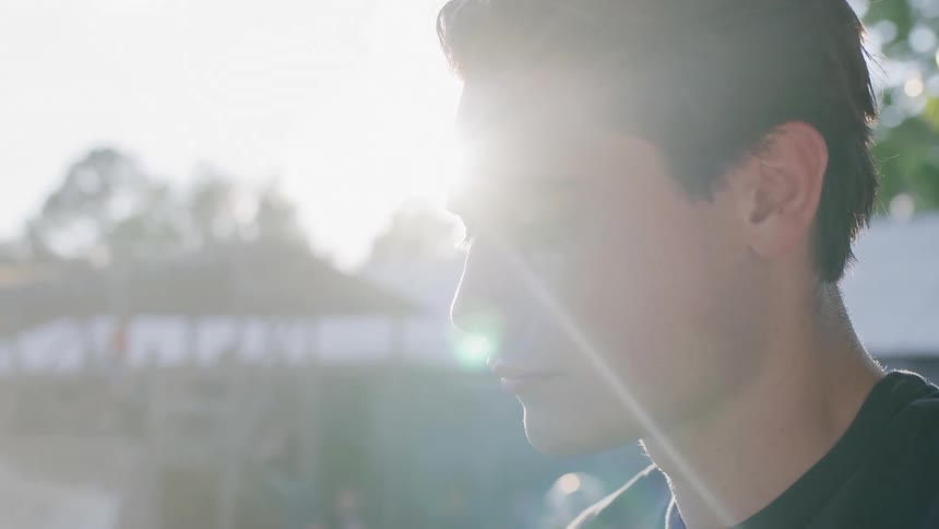 A young man stands lost in thought at a skateboarding park at midday