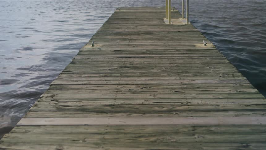 Wooden pier with metal railing extends over the water