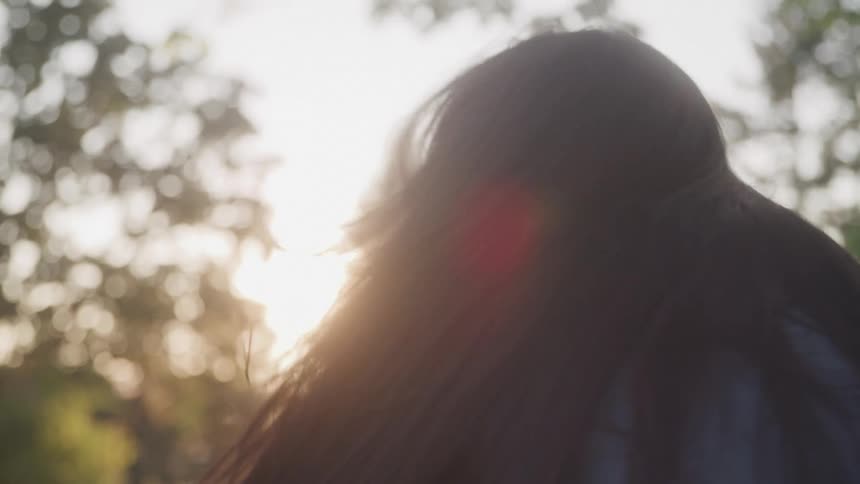 The video shows a young man giving a smiling woman a piggyback ride the woman is holding on to his neck and her hair is blowing in the breeze