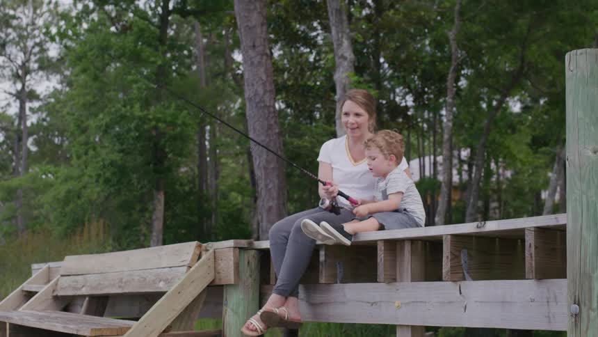 Woman and child fishing together on a wooden pier