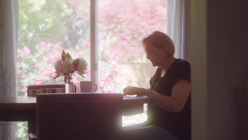 The woman is doing a puzzle at the table