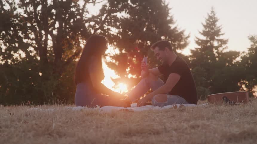 Happy couple enjoying a picnic outdoors at sunset