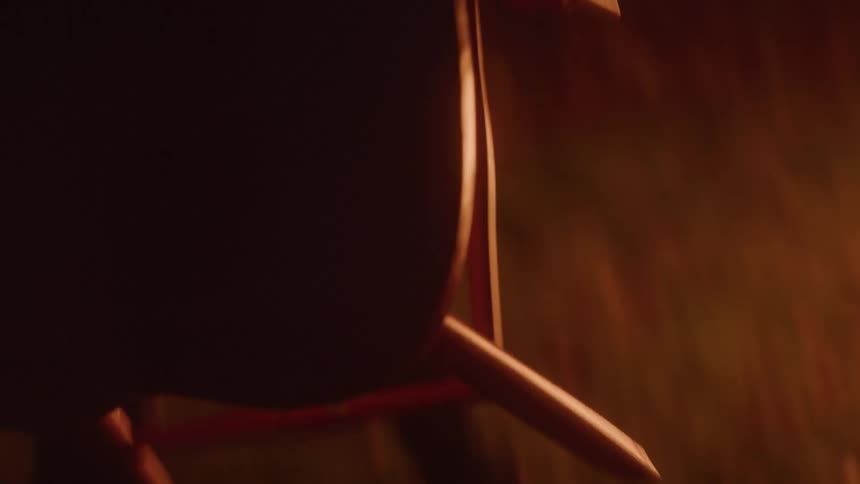 A person holds a chair and throws it in a fire in darkness