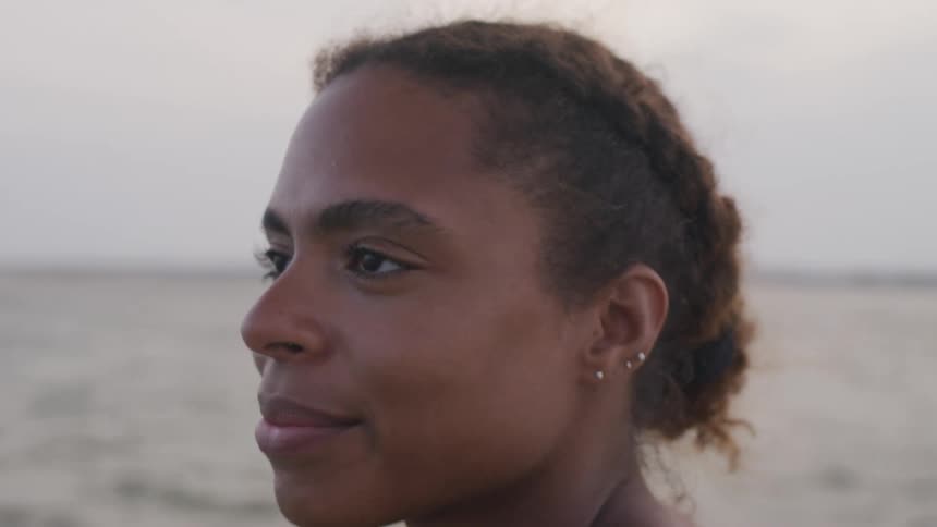 Woman gazing with smile at beach during sunset