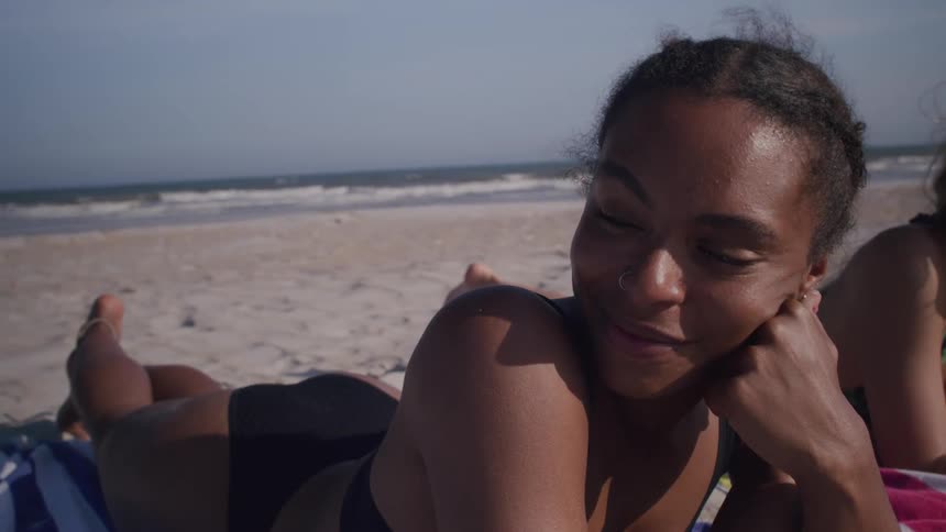 Woman lying on the beach on a breezy summer day smiles