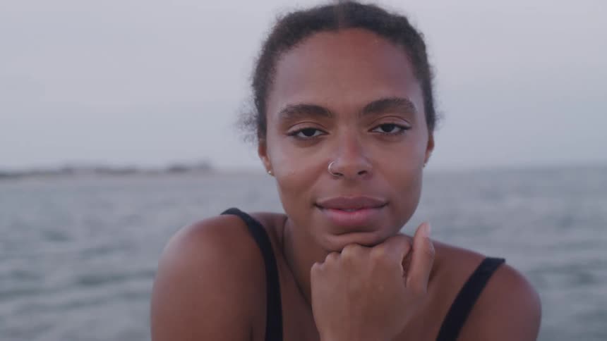 Woman looks calmly at camera near a body of water