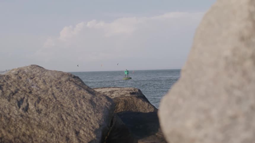Calm ocean with distant buoy and foreground rocks
