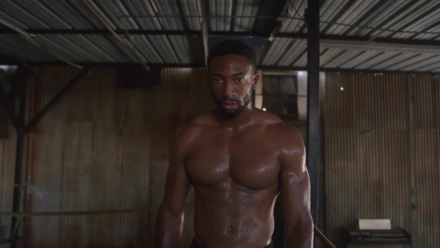 Shirtless sweaty man inside a warehouse