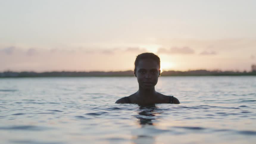 A female is standing in the ocean looking forward