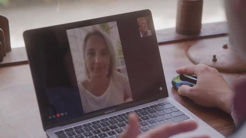 A woman appears on a video call smiling on a laptop screen during a conversation