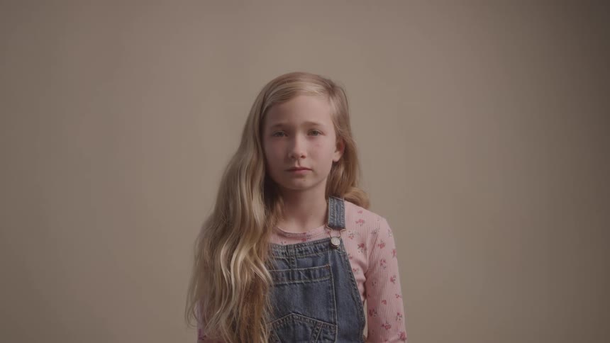 Portrait of a young blonde girl sitting in a room during daytime