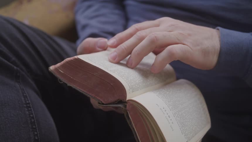 A person closely reads while gently touching its pages