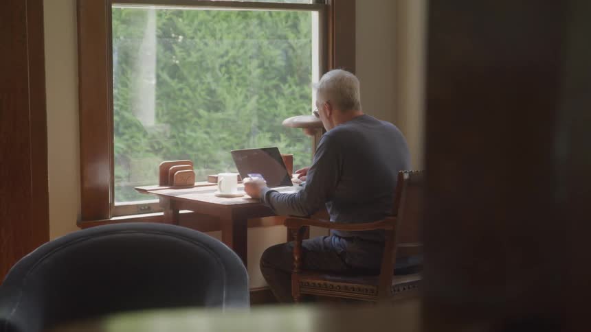 Man sitting at a table interacting with a laptop