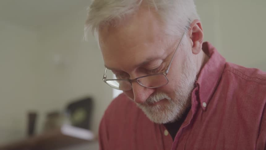 Man with white hair and beard in an interior space with glasses