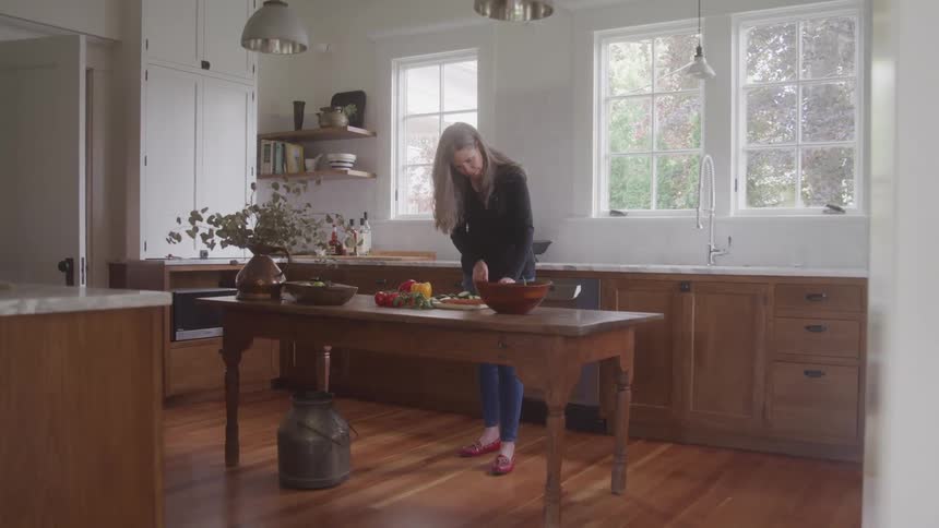 Woman prepares food on the wooden table in a bright kitchen