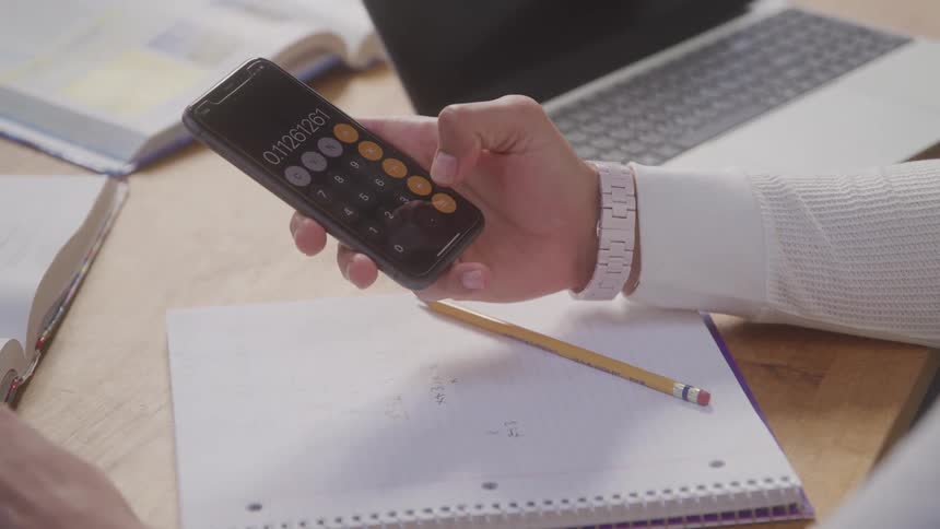 Person uses phone calculator while taking notes