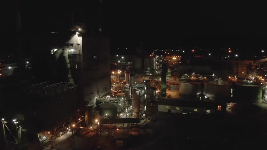 Large industrial complex lit at night with pipes and tanks