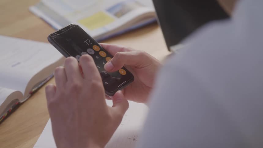 The video shows a person using a calculator app on a smartphone the persons hands are visible as they press the buttons on the screen