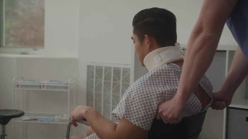 A nurse assists a man in a neck brace seated in a hospital