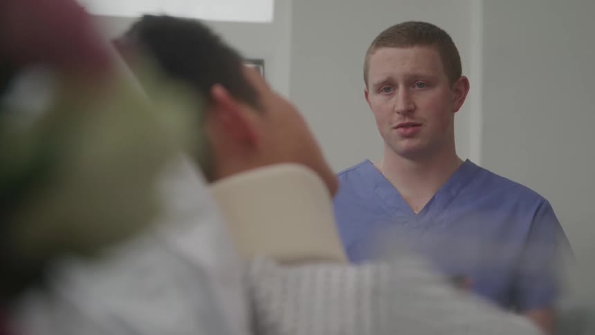 Healthcare worker observes a patient wearing a neck brace in a welllit room