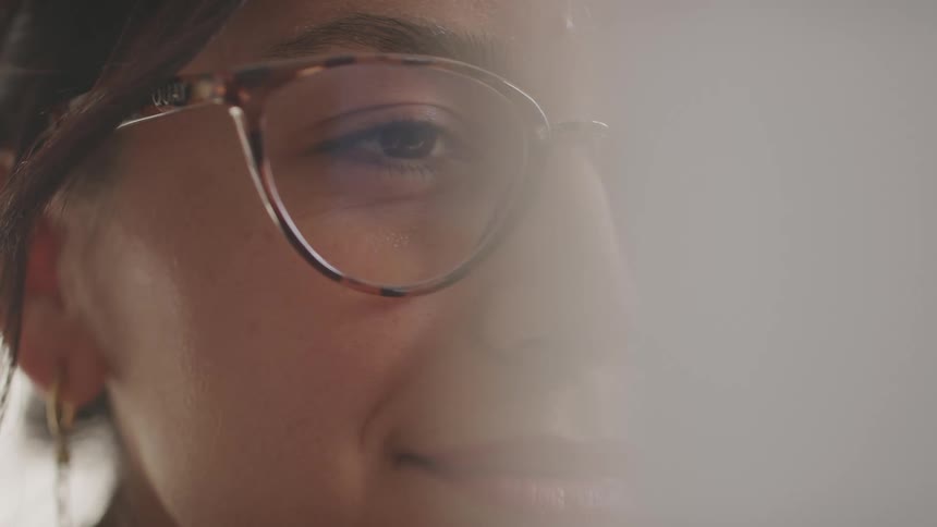 A closeup shot of a persons face with a focus on their eye and the tortoiseshellpatterned glasses they are wearing the person is looking offcamera