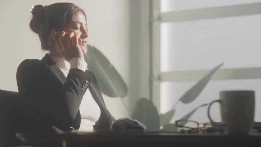 Businesswoman talks on the phone in a bright office