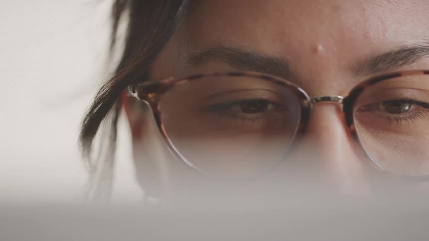 Close up of the face of a young woman reading with eyeglasses
