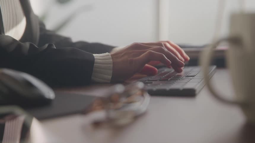 Close up of a woman using a desktop computer at a table in an office during daytime