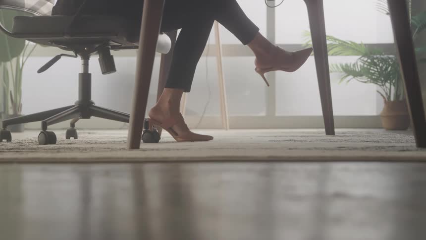 Legs of a woman in high heels sitting on a chair in an office environment