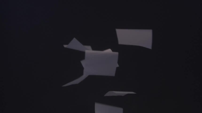Sheets of paper float in mid air against a dark background