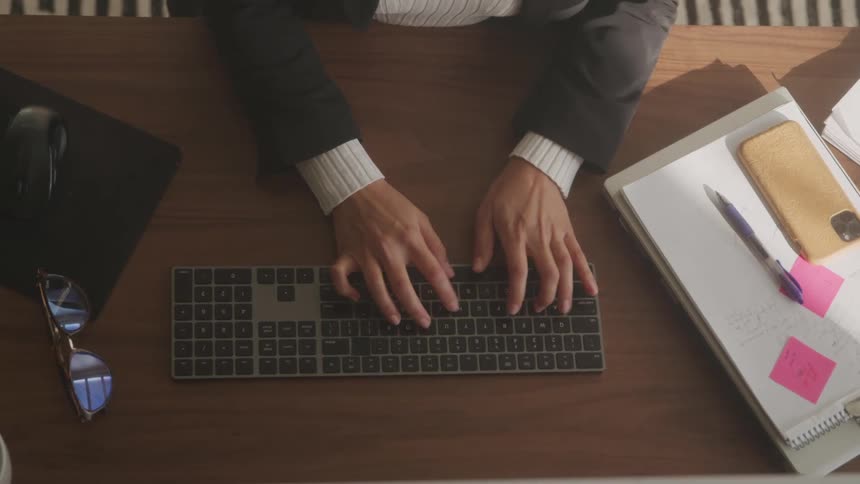 Hands typing on a computer keyboard on a desk