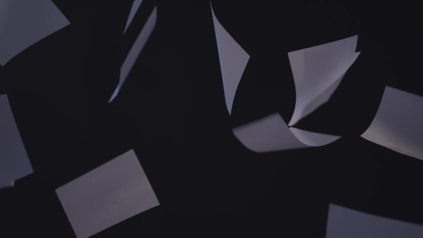 Sheets of paper float in the air against a dark background