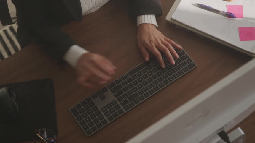Hands type on a keyboard over an organized work desk