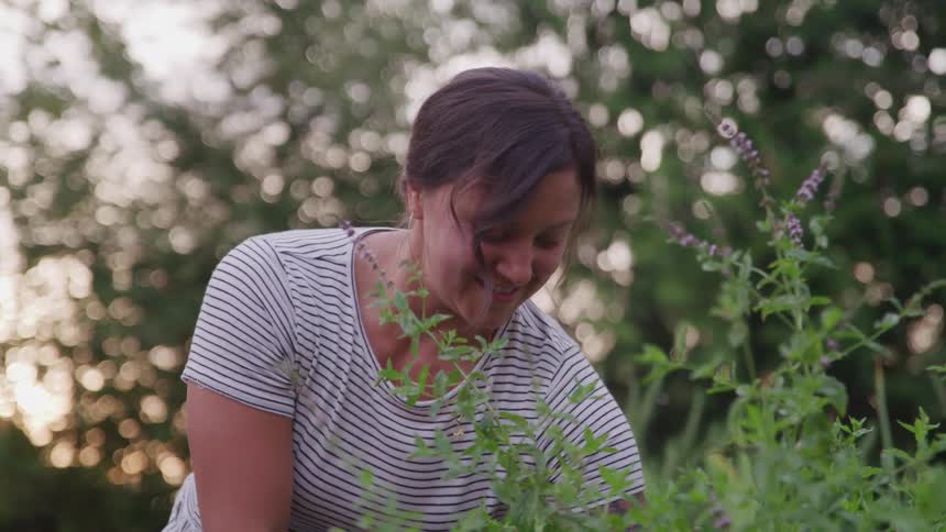 A woman tends to her garden on her lawn at midday