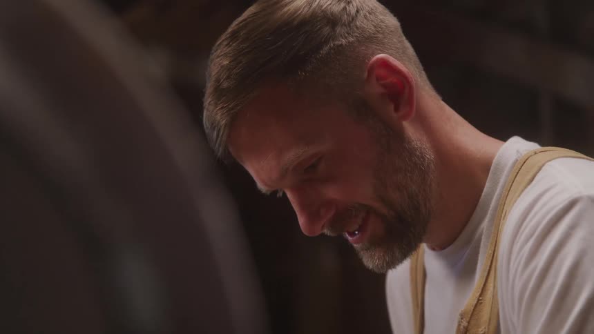 Man smiles while working wearing a light apron