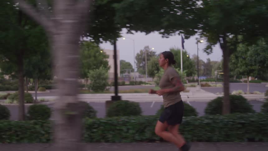 Woman jogs on a treelined street at dusk