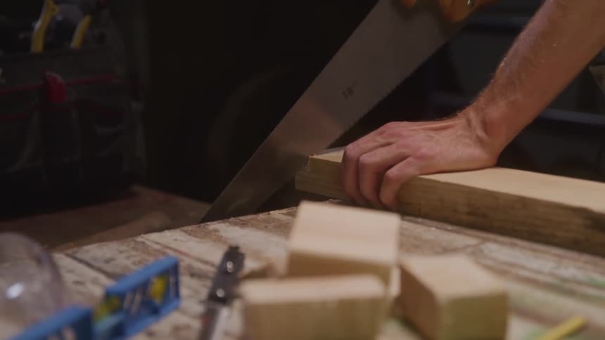 The man is sawing a plank of wood