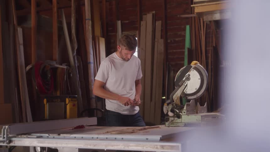 The carpenter is using a tool in his shop