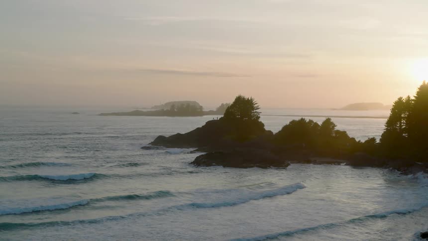 Sun sets over the sea illuminating rocky islands covered with trees