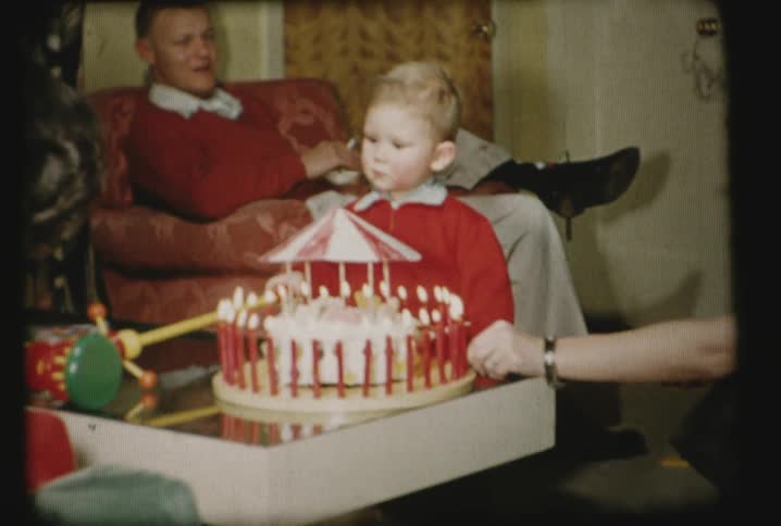 A cake is put on the table in front of a child