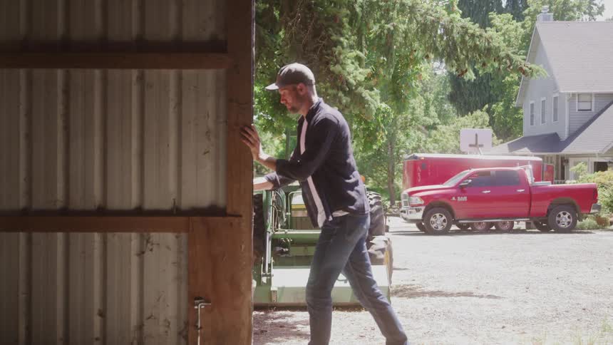 The man is pushing the barn door open