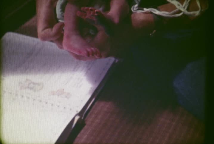 A person presses ink on a babies foot and takes a footprint
