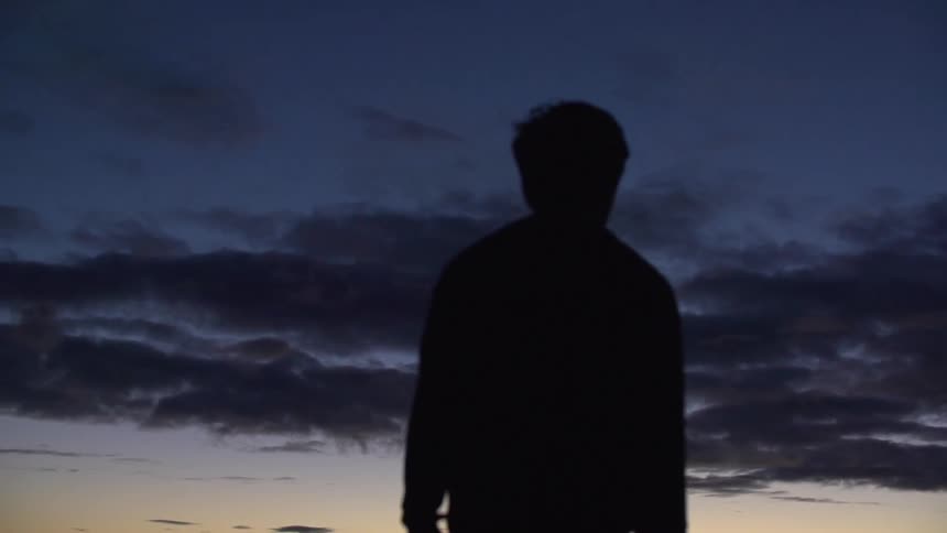Man walking as he looks at the sky at sunset