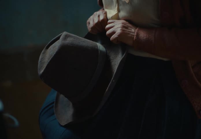 Person on knees holding a hat
