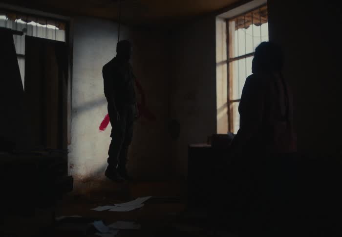 Silhouette of a woman watching a dead man on a gallows rope