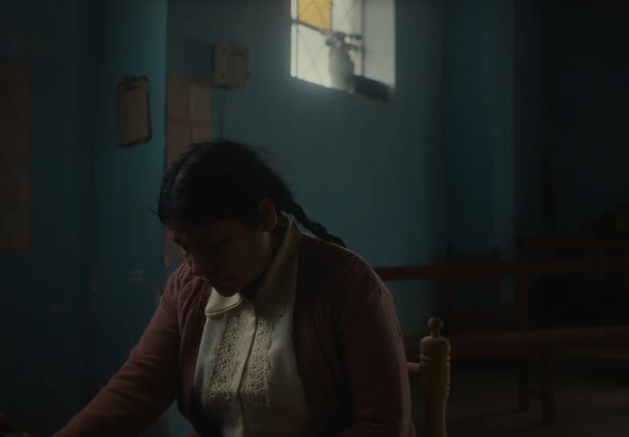 A woman sits sad and distressed in a dim room