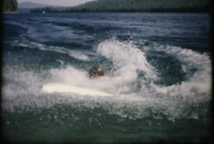 A boy falls off a wakeboard and wipes his face