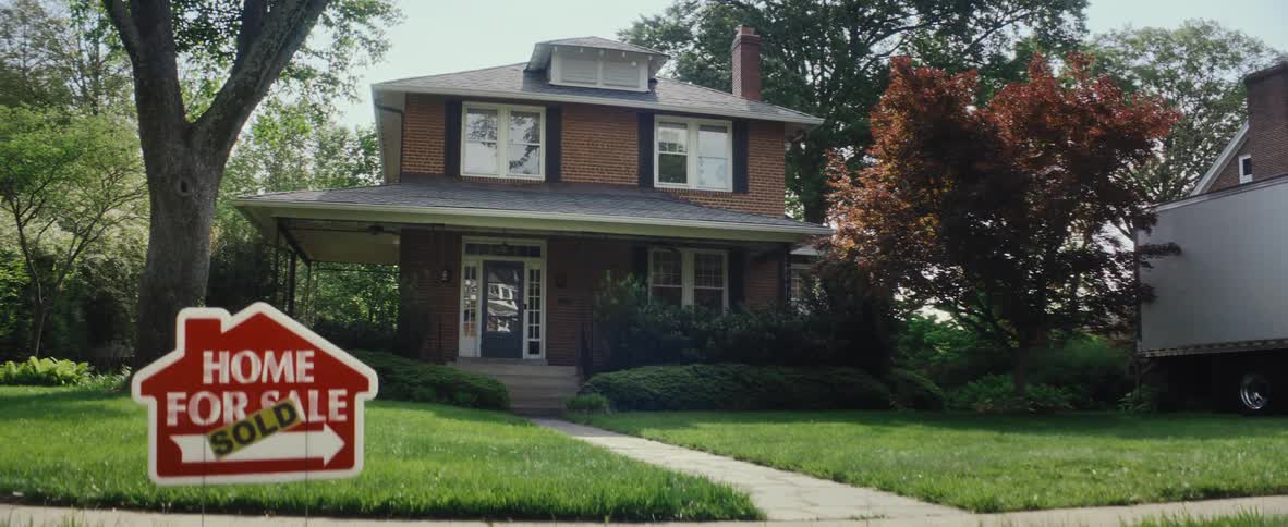 Home for sale sign in front of a residential home in a neighborhood
